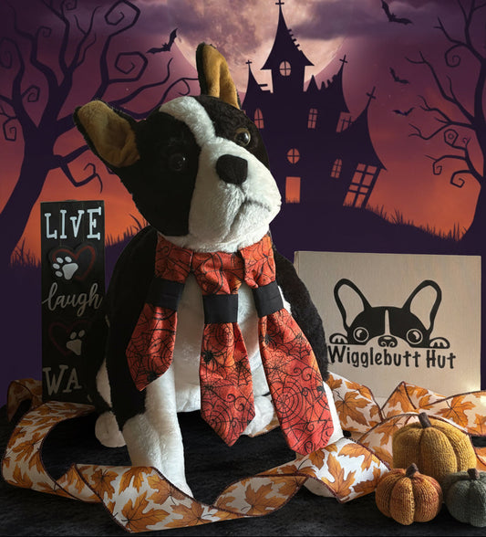 Plush dog toy with a scarf on a beige background, featuring a brand logo and text.